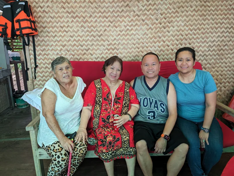 Family members seated on a red couch with a bamboo wall backdrop in Palawan, Philippines