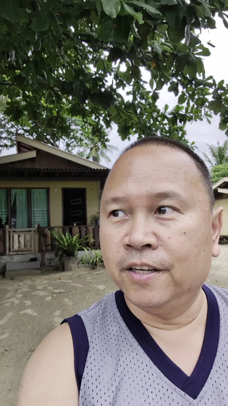 Man taking a selfie in front of a traditional-style house in Palawan, Philippines
