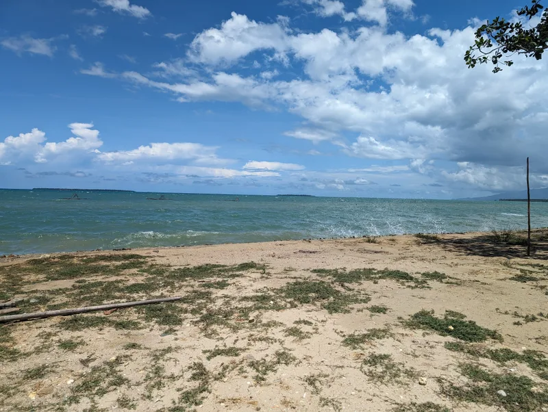 Wide sandy shoreline in Palawan facing the blue ocean under a cloudy sky