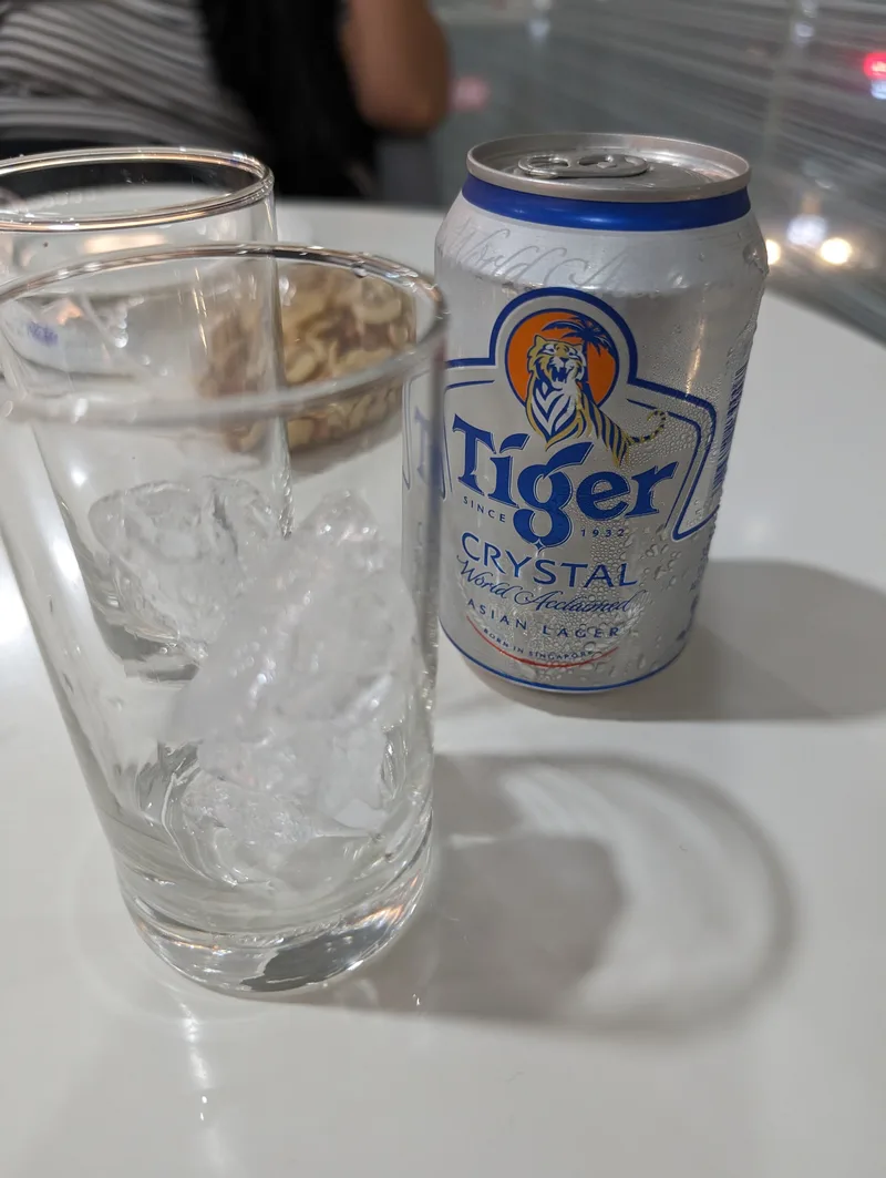 Chilled can of Tiger Crystal beer on a white table next to two glasses one filled with ice with condensation on the can at a hotel in Puerto Princesa, Palawan, Philippines