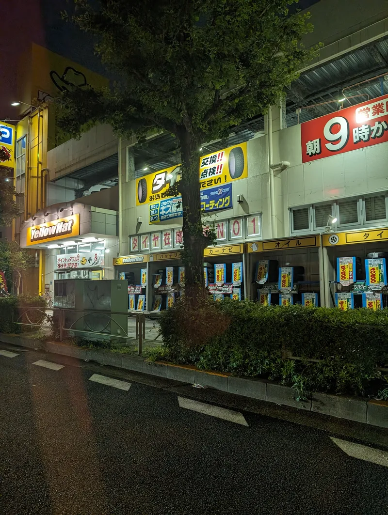 Yellow Hat auto parts store illuminated at night in Japan.