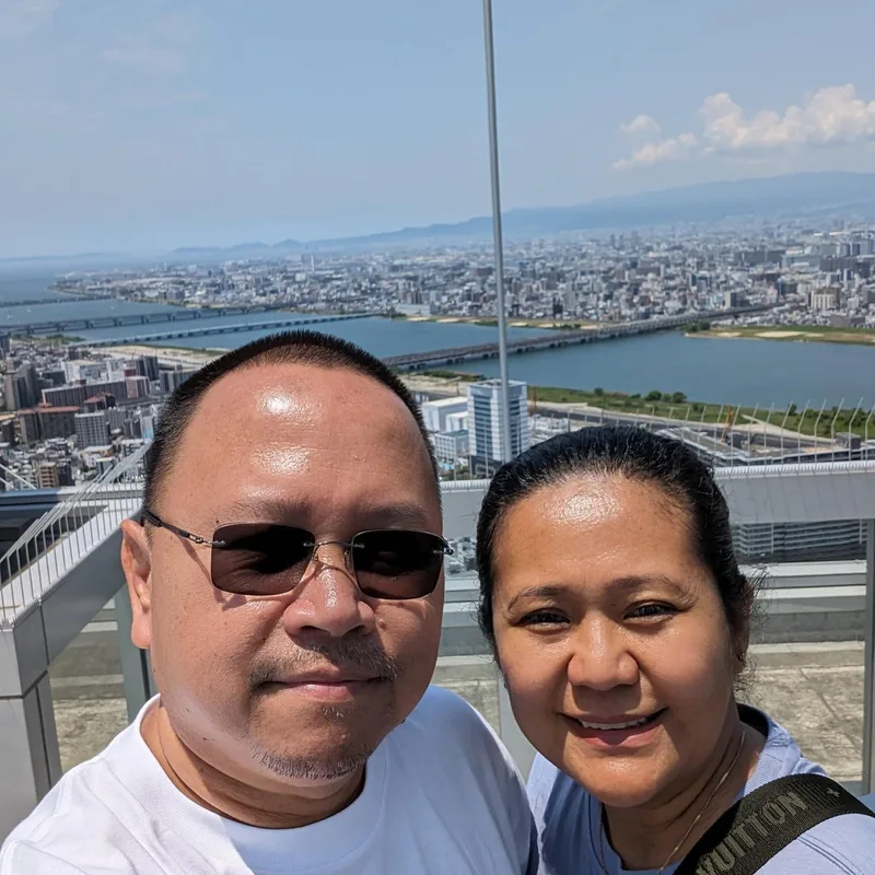 Couple selfie on the Umeda Sky Building rooftop with panoramic Osaka city view, Japan.
