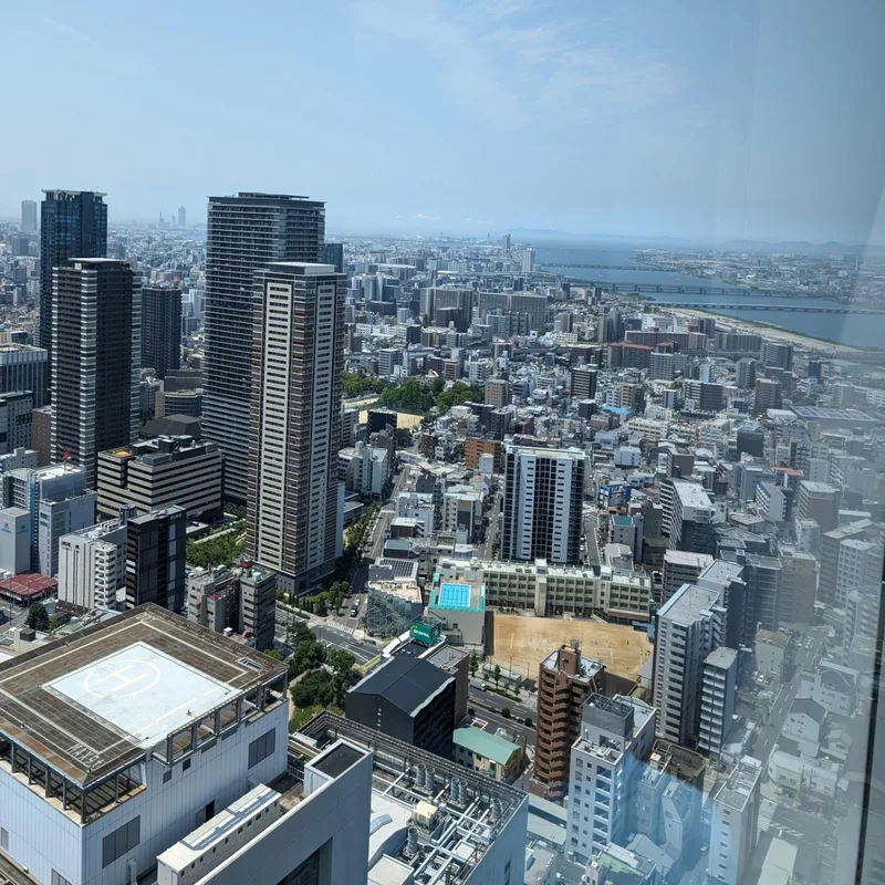 Panoramic Osaka cityscape from Umeda Sky Building rooftop showing river and mountains, Japan.