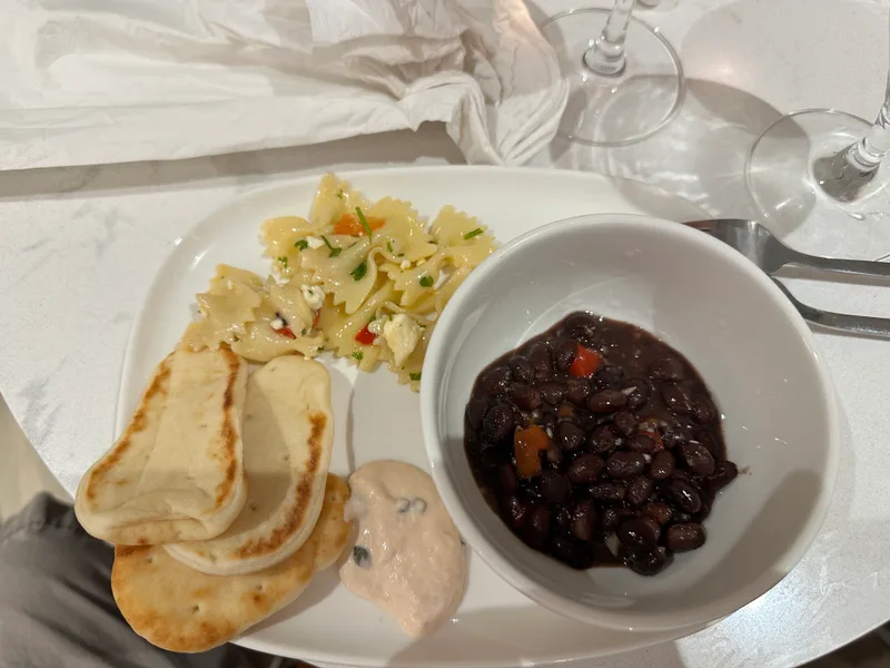 Delta Sky Club meal with pasta salad, black beans, and naan bread