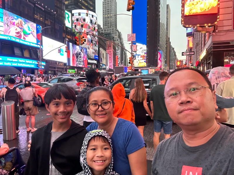Family selfie in Times Square with bright billboards and skyscrapers
