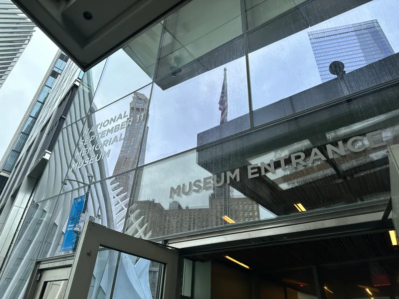 Glass entrance of National September 11 Memorial Museum reflecting buildings
