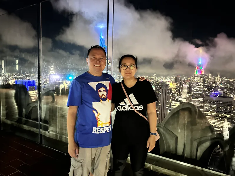 Couple on NYC rooftop with illuminated skyline and Empire State Building at night