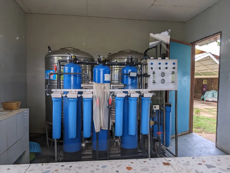 Water purification system with large stainless steel tanks and blue filter cartridges inside an open building at Henalric resort in Palawan Philippines