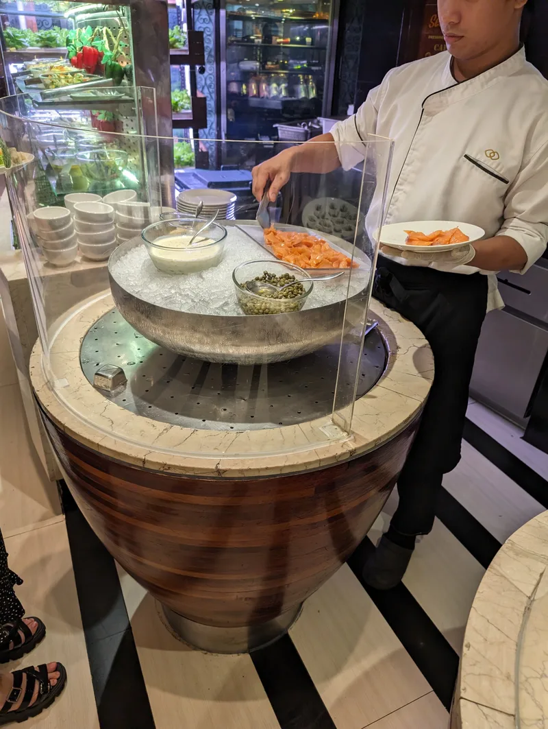Chef serving smoked salmon and capers from an ice-filled bowl at the Spiral buffet at Sofitel Philippine Plaza, Manila.